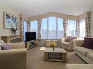 a living room with couches and a tv at Pheasant Lodge in Holyhead