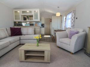 a living room with a couch and chairs and a table at Pheasant Lodge in Holyhead