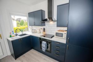 a kitchen with blue cabinets and a microwave at Limefield Residence in West Calder