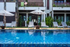 a swimming pool with chairs and umbrellas next to a building at Beachfront! 2 Bedroom Apartment A4 - 110 Sqm in Ko Bu Bu