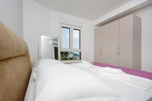 a bedroom with a white bed and a window at Sunset Apartments in Makarska