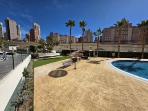 a swimming pool with a bench and an umbrella at Apartamento Luxury Views IF Benidorm in Benidorm