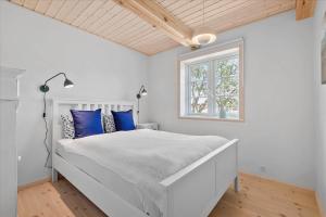 a white bedroom with a large bed with blue pillows at 0145-Romo-Hattesvej-36 in Høm