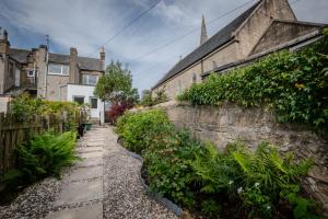 a stone wall next to a house with plants at Limefield Residence in West Calder