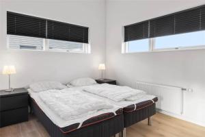 a bedroom with a large bed with two windows at 0347-Romo-Vestergade-353 in Høm