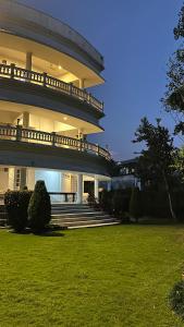 a large building with stairs and grass in front of it at Boutique Villa w Bonfire & BBQ, Mussoorie Foothills in Dehradun