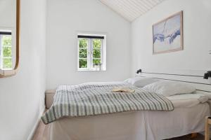a white bedroom with a bed and two windows at 0130-Romo-Ejnar-Mikkelsensvej-22 in Høm