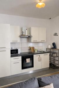 a kitchen with white cabinets and a stove top oven at Au Petit Colombage - Cosy au centre de Mulhouse - Gare proche in Mulhouse