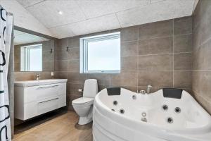 a bathroom with a white tub and a toilet and a window at 0308-Romo-Vagtelvej-4 in Høm +26 photos