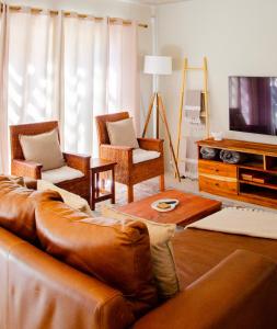 a living room with a brown leather couch and chairs at Rustic Hills No 3 Self Catering in Swakopmund