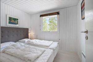 a white bedroom with a large bed with a window at 0424-Romo-Sonderstrandvej-15 in Høm