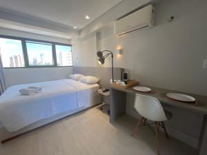 a white bedroom with a bed and a desk and a desk at Manaíra Apart Hotel in João Pessoa +62 photos
