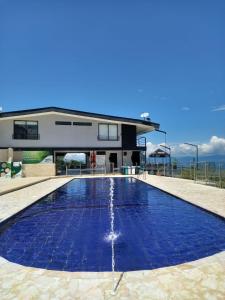 a swimming pool with blue water in front of a house at ZOI Eco Hotel y Glamping in Manizales