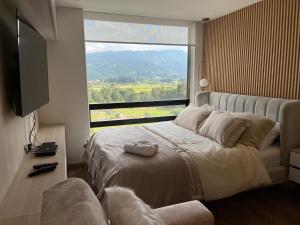a bedroom with a bed with a large window at GV Aparta Suites - Centro Chía in Chía