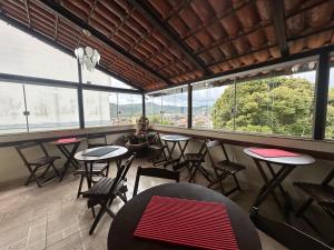 a person sitting at a table in a room with windows at Pousada Vila Catarina in Ouro Preto
