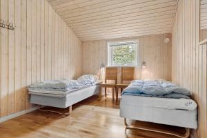 two beds in a room with wooden walls and a window at 0317-Romo-Sonderstrandvej-24 in Høm