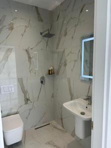 a white bathroom with a sink and a toilet at Qyteza guest house in Shkodër