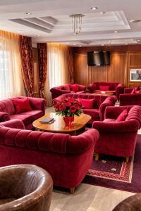 a waiting room with red couches and a tv at Spa Hotel Dvoretsa in Velingrad