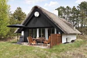 a house with a thatched roof with a table and chairs at 0309-Romo-Stagebjergvej-13 in Høm