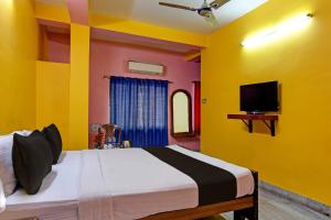 a bedroom with yellow walls and a bed with a tv at Hotel O by OYO Red Rose Near Noapara Metro Station in Kolkata