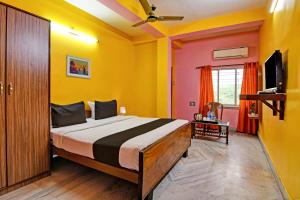a bedroom with a bed with yellow walls and a tv at Hotel O by OYO Red Rose Near Noapara Metro Station in Kolkata