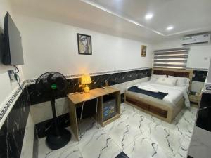 ein Schlafzimmer mit Bett, Schreibtisch und Fernseher in der Unterkunft Mathelm Hotel in Ikorodu