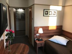 a small room with a bed and a table with a vase of roses at Hotel & Restauracja Glass in Radom