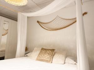 a bedroom with a canopy bed with white sheets and pillows at Kalma - at the picturesque Via Stretta in Cagliari