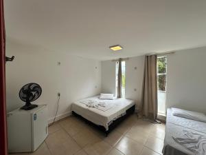 a white bedroom with a bed and a window at Pousada Vila Catarina in Ouro Preto