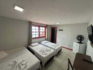 a room with two beds and a desk and a television at Pousada Vila Catarina in Ouro Preto