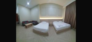 a hotel room with two beds and a couch at Mabit Hotel Syariah in Takengon