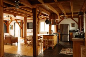 a kitchen and living room with wooden ceilings and a table at Fawn Crest -Timber Frame Retreat, Firepit, 20 acre in Alfred Station