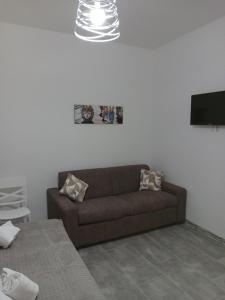 a living room with a brown couch and a tv at Nel cuore di Segesta in Calatafimi
