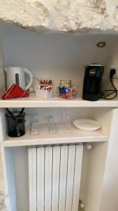 a white shelf with cups and a coffee maker at Suite Prima Pietra con Piscina idromassaggio riscaldata in Ostuni