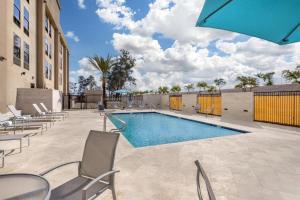 a swimming pool with chairs and an umbrella at Best Western Plus Gilbert/Mesa in Mesa
