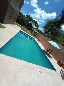 a swimming pool with an umbrella and a chair at Cabaña Doña Adela II in Paso de la Patria