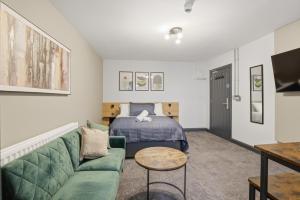 a living room with a green couch and a bed at Clayton Apartments in Newcastle upon Tyne