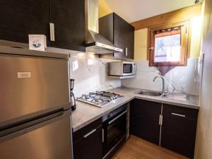 a kitchen with a stainless steel refrigerator and a sink at ZEcamping 3 étoiles animaux acceptés restaurant et Canoë Kayak in Aigueblanche