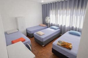 ein Zimmer mit drei Betten und einem Stuhl in der Unterkunft Hotel Pousada Liberdade in Pindamonhangaba