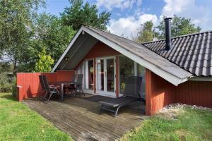 a red cabin with a table and chairs on a deck at 0146-Romo-Ejnar-Mikkelsensvej-16 in Høm