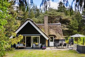 a cottage with a thatched roof with chairs and tables at 0337-Romo-Kliren-1 in Høm