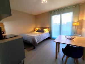 a bedroom with a bed and a table and a window at Studio Rénové - Le Verdale in Lamalou-les-Bains
