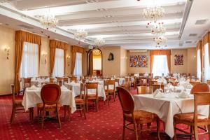 a dining room with tables and chairs and chandeliers at Spa Hotel Dvoretsa in Velingrad