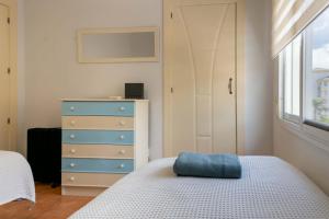 a bedroom with a bed and a dresser with a blue pillow at Apartamento ROMA in Torre del Mar +5 photos