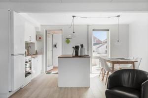 a white kitchen with a table and a black chair at 0353-Romo-Vestergade-155-B-Ap-130 in Høm