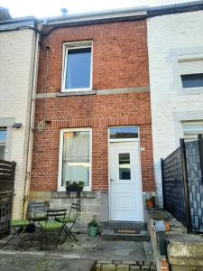 a brick house with a white door and a table at L'Ultra Pause au cœur du Viroin in Olloy-sur-Viroin