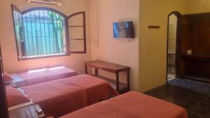 a hotel room with two beds and a window at Pousada TURI in Caraguatatuba