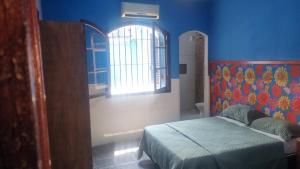 a blue bedroom with a bed and a window at Pousada TURI in Caraguatatuba