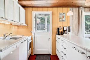 a kitchen with white cabinets and a white door at 0028-Romo-Blabaervej-28 in Høm +13 photos