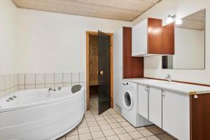 a bathroom with a tub and a sink and a washing machine at 0462-Romo-Romersvej-9-Ap-2 in Høm +21 photos